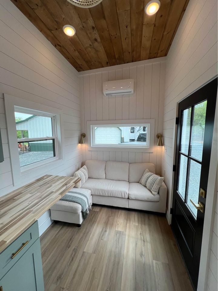 Cozy tiny house living room with white sofa, wood accents, and natural light. Perfect for small spac.