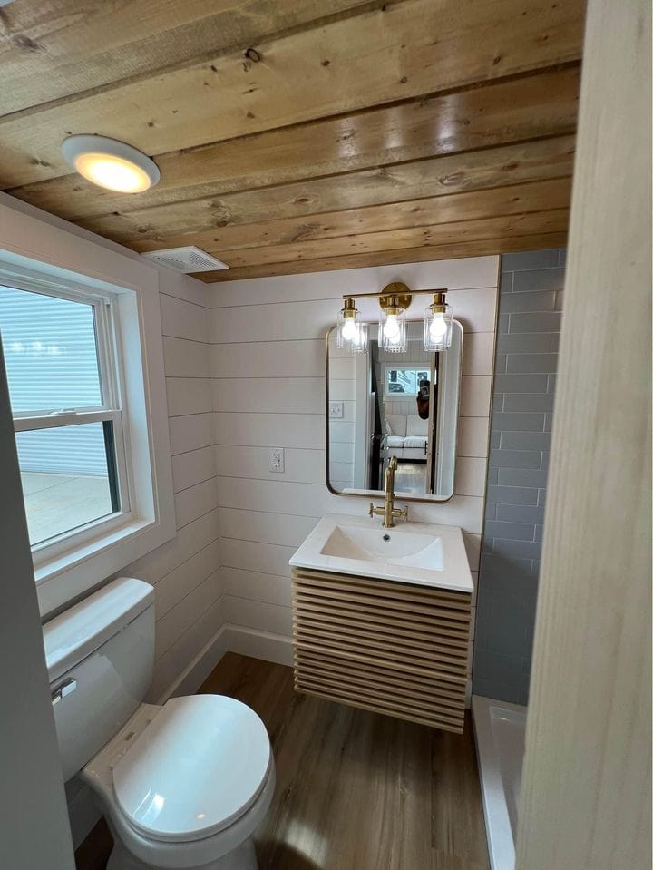 Small farmhouse bathroom with wood accents, modern sink, and lighting.