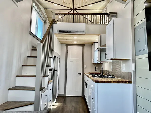 Cozy tiny house interior with compact kitchen and loft space on wheels.