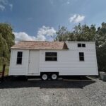 Coastal tiny house on wheels with white exterior, perfect for small space living and mobility.