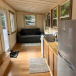 Compact tiny house interior with single-level design and large windows.