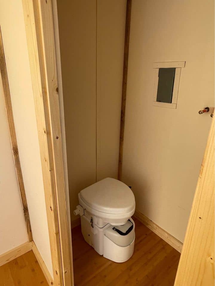 Compact tiny house bathroom with toilet and minimal design.