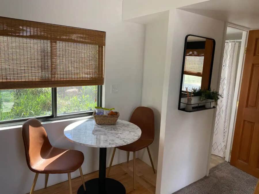 Adorable 250 sq. ft. casita with a compact dining nook featuring a marble table and two stylish chai.