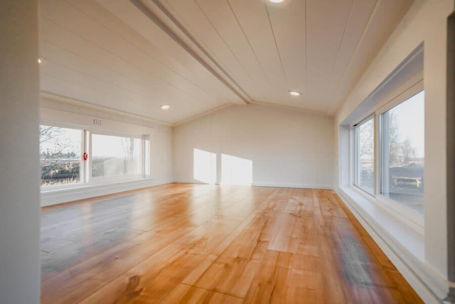 Bright and spacious tiny house interior with large windows and wooden floors.