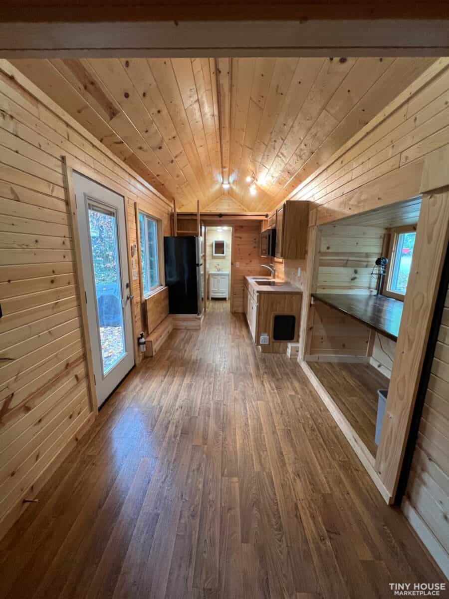 Compact tiny house interior featuring a 28′ lift bed and efficient kitchen space. Perfect for small.