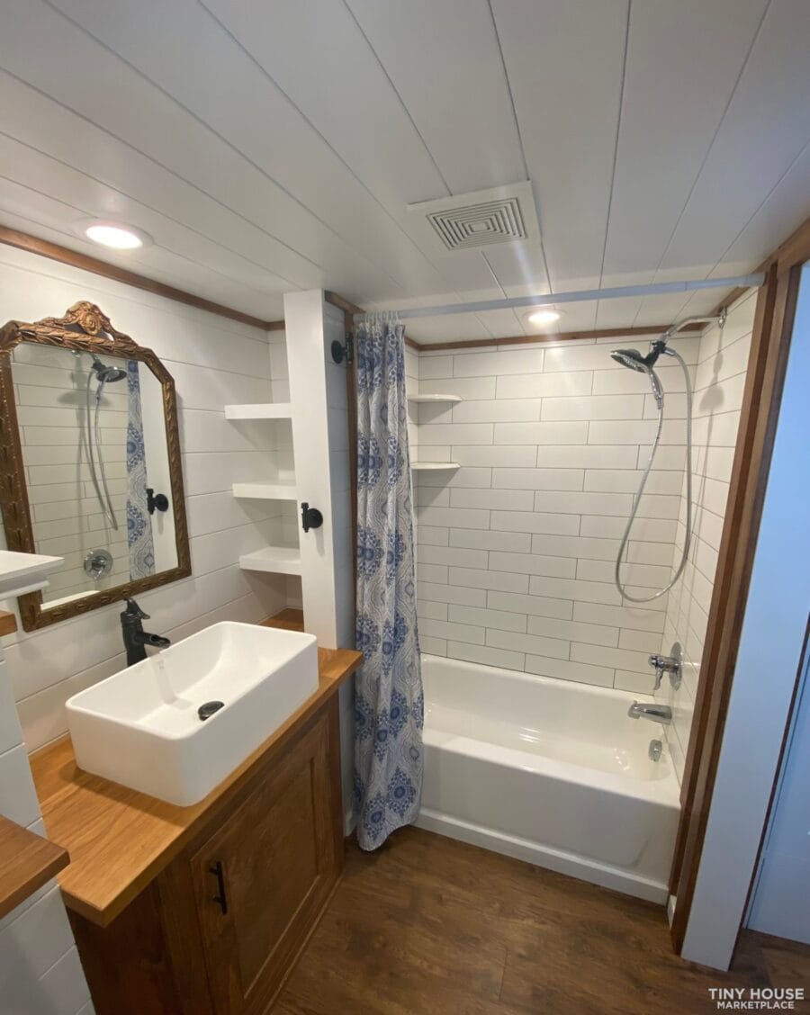 Compact tiny house bathroom with a stylish white bathtub and vessel sink. Perfect for small space li.