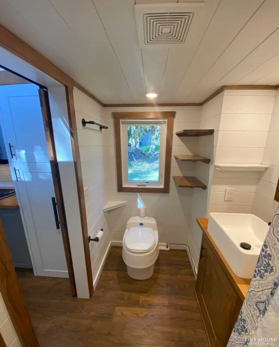 Tiny house bathroom with modern fixtures and wooden shelves.