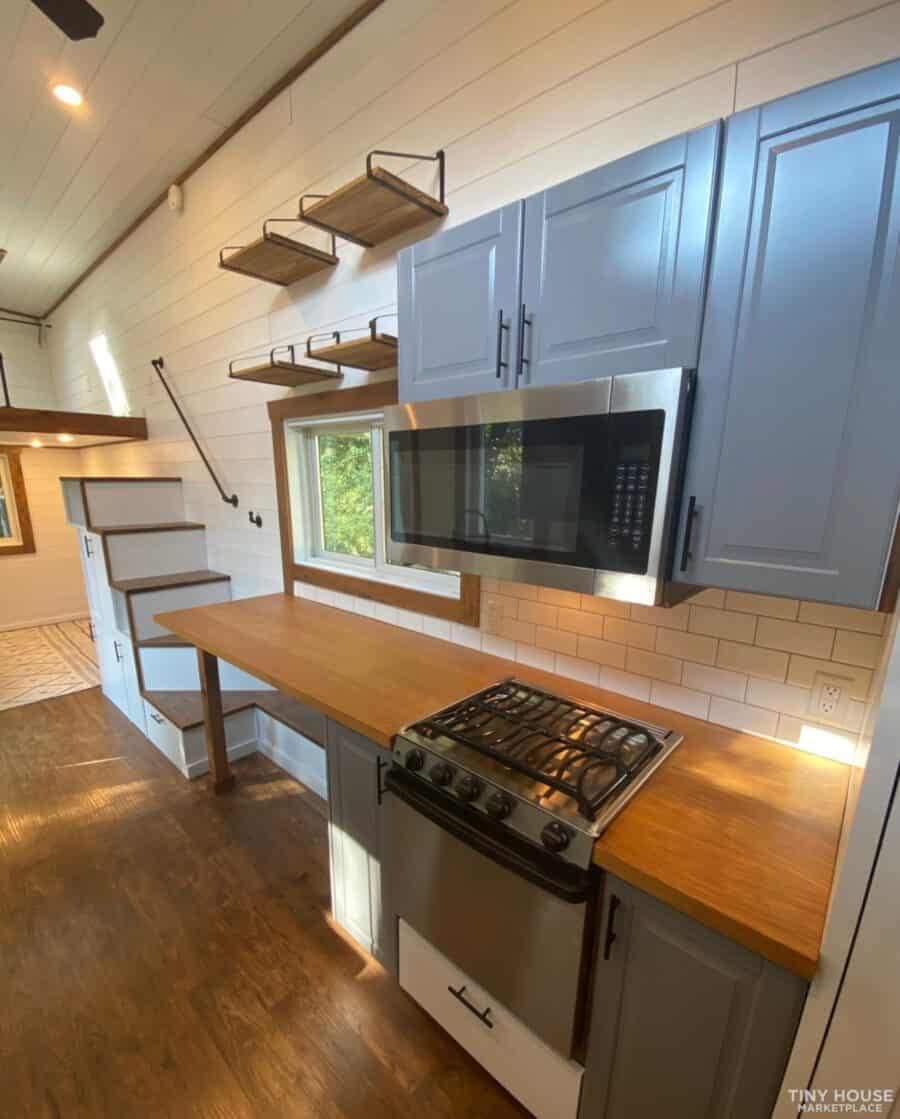 Compact tiny house kitchen with blue cabinets and wooden countertops.