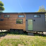 Tiny house on wheels with modern design and mixed wood and metal exterior.