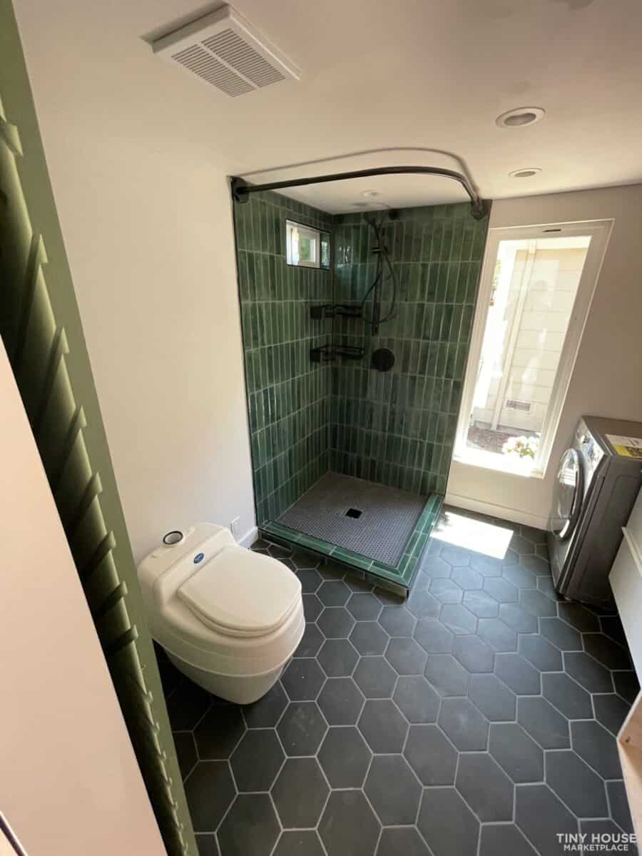 Compact tiny house bathroom featuring a green-tiled walk-in shower and modern fixtures.
