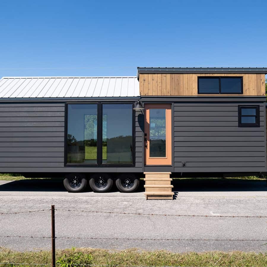 Tiny house on wheels with spacious walk-around queen bedroom and modern exterior design.
