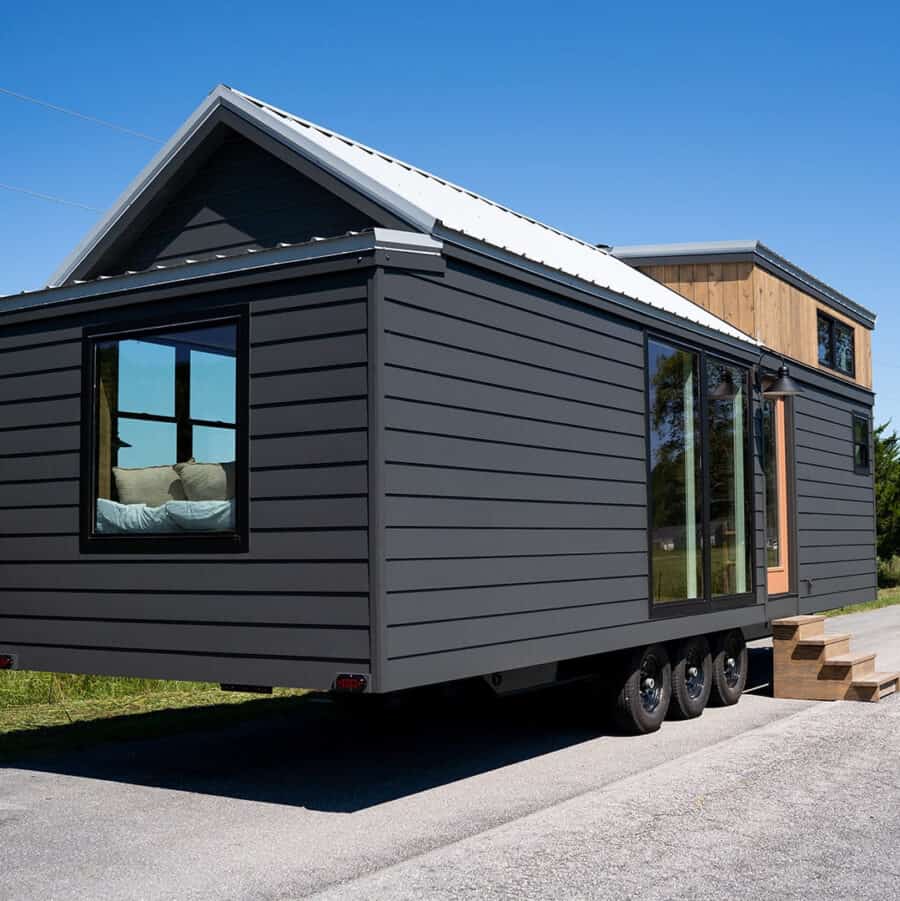 Compact tiny house with sleek black exterior and large windows.