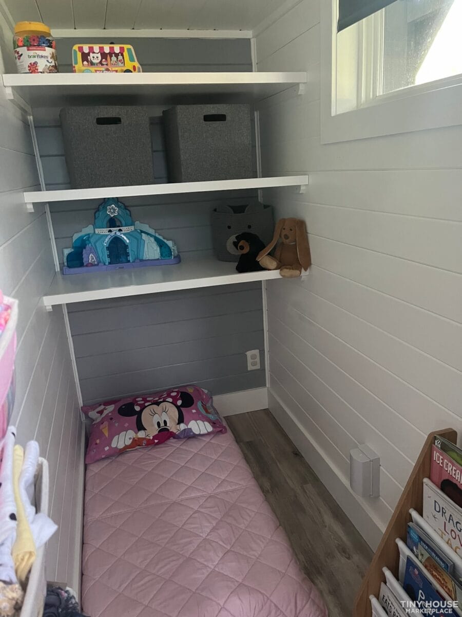 Tiny house interior with storage shelves and plush toys.