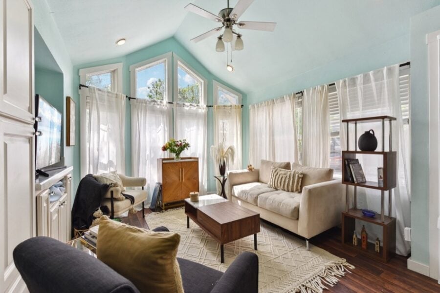 Bright, airy tiny house interior with large windows and comfortable seating.