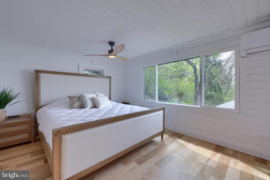 Bright and airy tiny house bedroom with a large window overlooking lush greenery.
