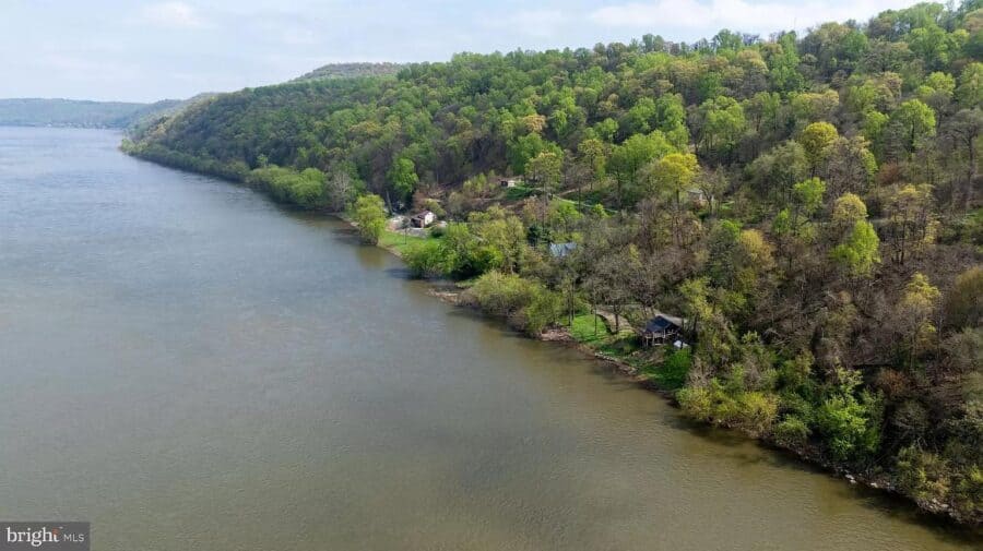 Small cottage nestled on 3 acres with lush trees and river views in Pennsylvania.