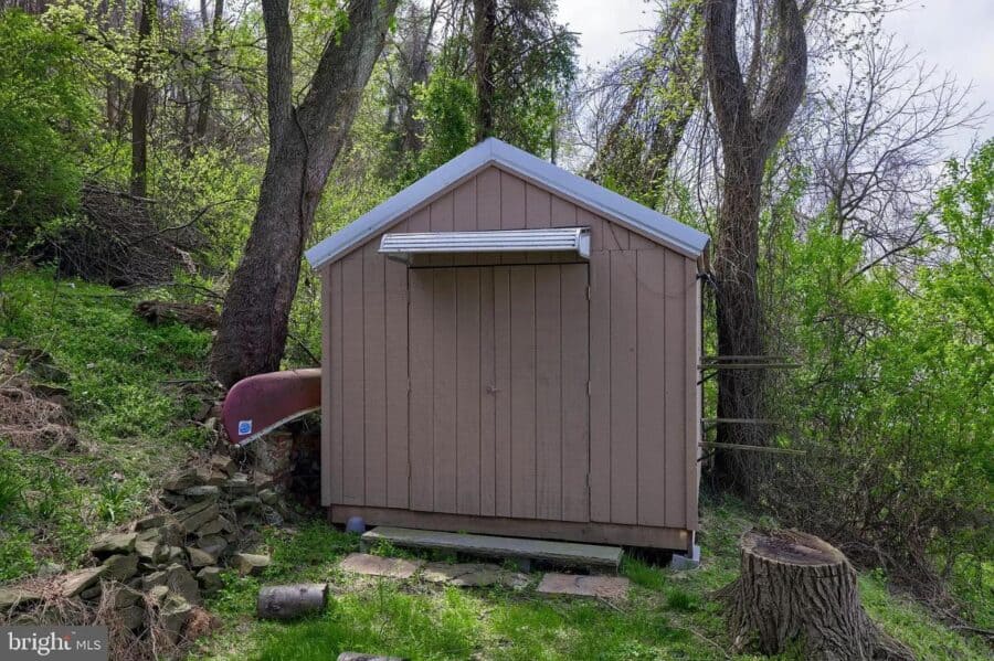 Tiny house shed in wooded landscape, surrounded by trees and greenery.
