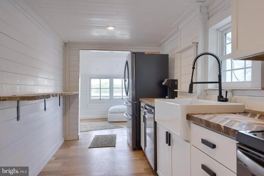 Compact tiny house kitchen with modern appliances and farmhouse sink.
