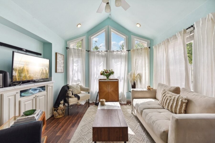 Bright and airy tiny house interior with large windows and comfortable seating.