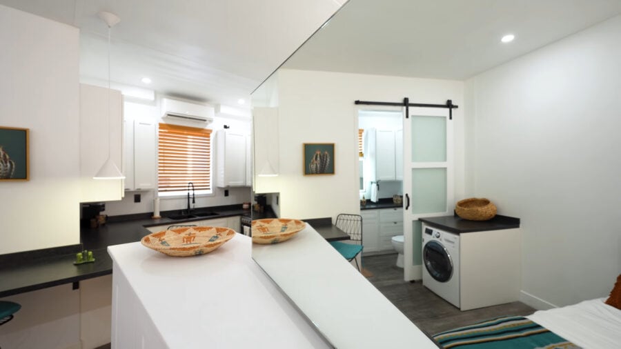 Bright tiny house interior featuring foldable walls and compact appliances for small space living.