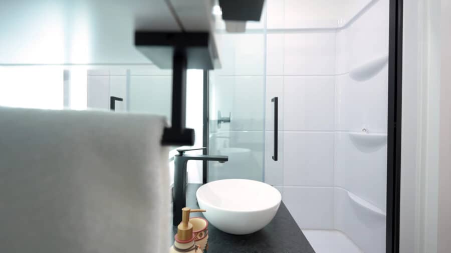 Modern tiny house bathroom with sleek fixtures and white tiles.