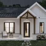 Small white cottage with front porch, black roof, and garden, perfect for tiny house living.
