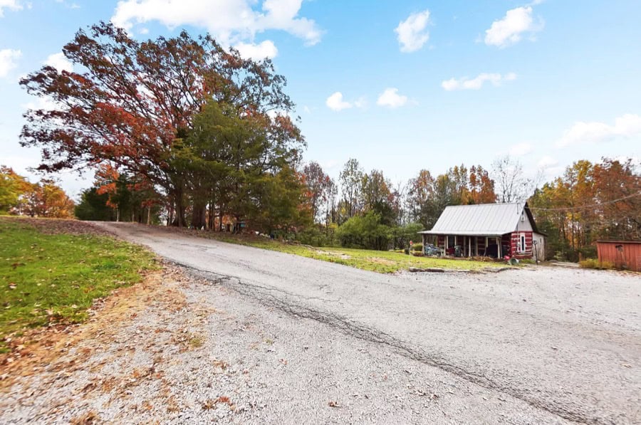 Rustic log cabin nestled on spacious 5-acre property in Kentucky, surrounded by colorful fall trees.