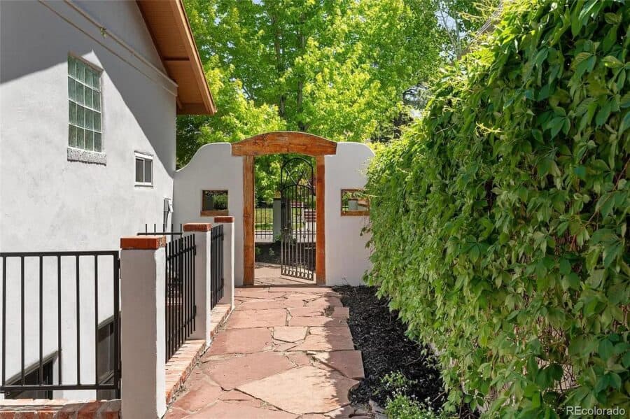 Beautiful Spanish-style home entrance with a stone pathway and lush greenery. Perfect for small spac.