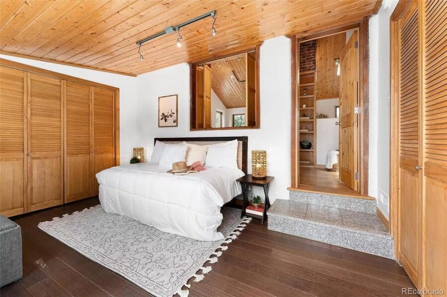 Cozy tiny house bedroom with wooden walls and ceiling, modern decor, and compact design.