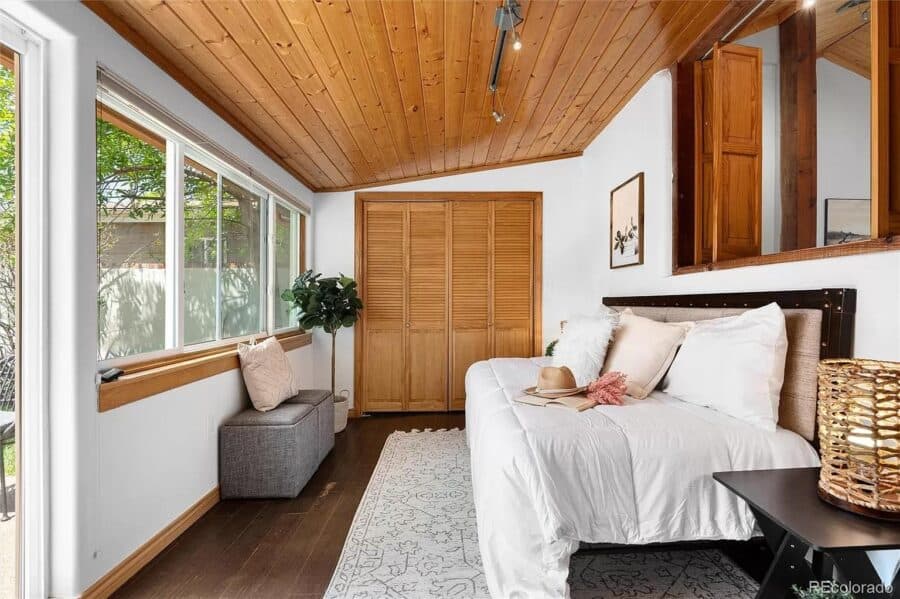 Bright tiny house bedroom with wooden ceiling, large window, and cozy decor for small space living.