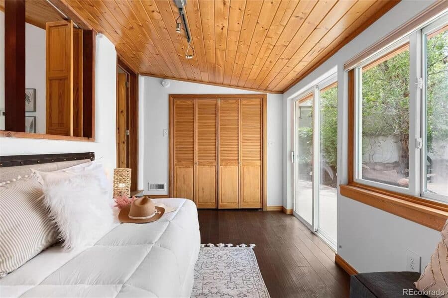 Bright small house interior with large windows and wooden ceiling.