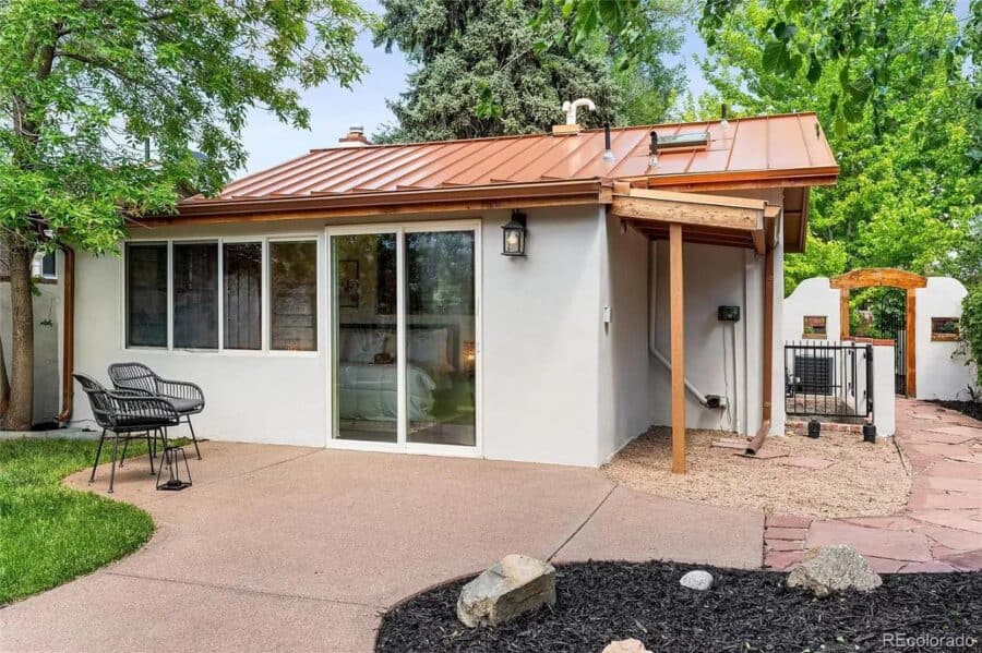 Charming tiny house featuring a Spanish-inspired design, attached garage, and outdoor seating area f.