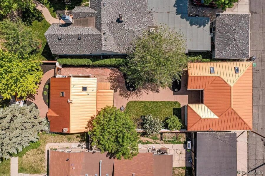 Aerial view of a 786 sq. ft. Spanish-style tiny home featuring a detached garage and lush landscapin.