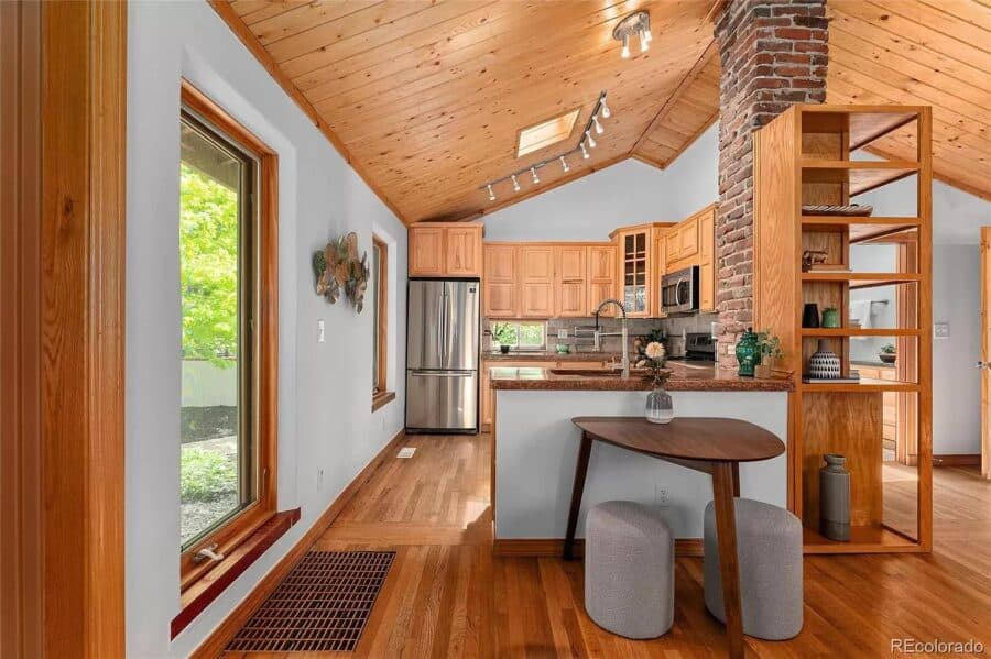 Bright interior of a tiny house featuring a wooden ceiling, kitchen with stainless steel appliances,.