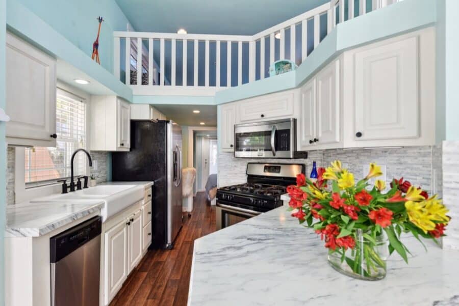 Bright tiny house kitchen with white cabinets and marble countertops near Austin.