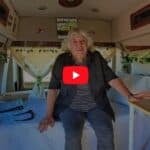 Elderly woman enjoying her tiny house interior, showcasing minimalist living and comfort in a small.