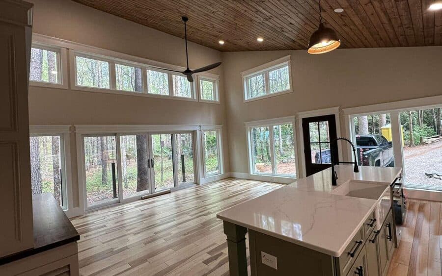 Bright interior of a small house with large windows and a dramatic roofline, showcasing open living.
