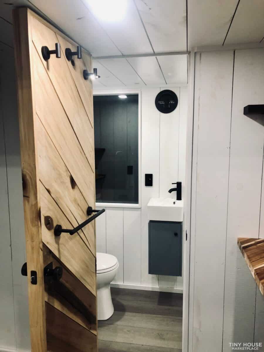 Compact tiny house bathroom with modern fixtures and wood accents.