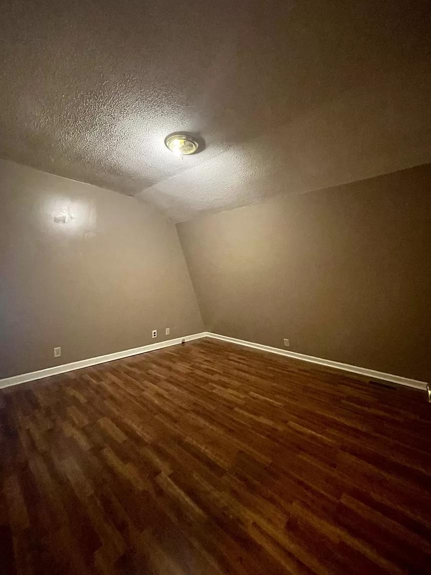 A-Frame home interior featuring a spacious room with wooden flooring and neutral wall colors, showca.