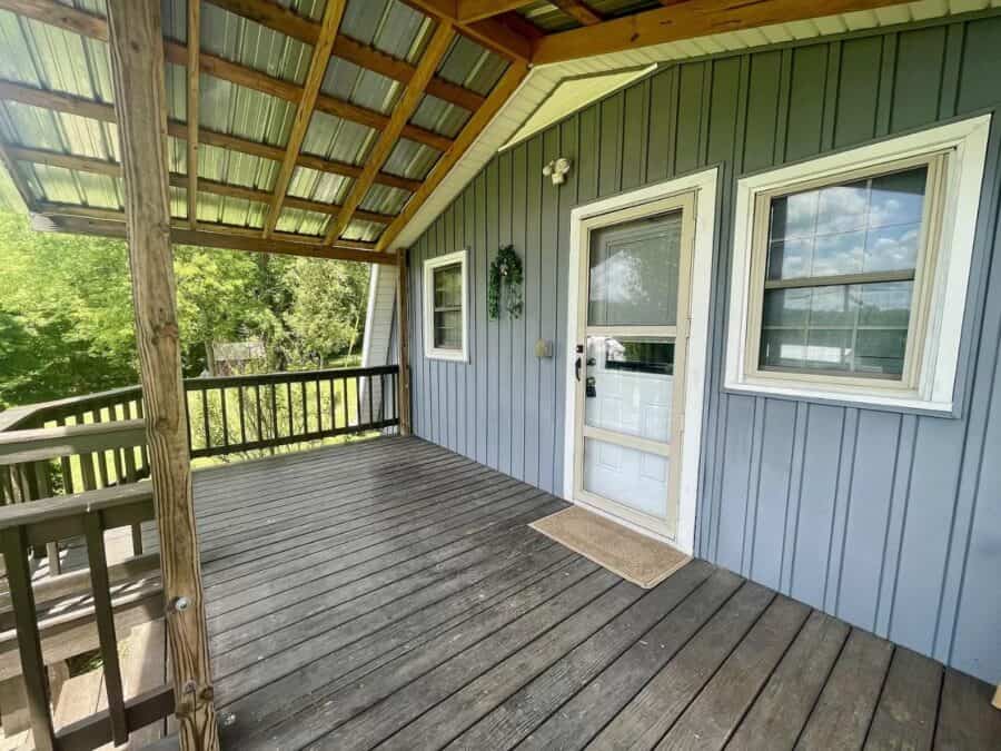 A-Frame tiny house with metal roof and siding, featuring a spacious porch and large windows for natu.