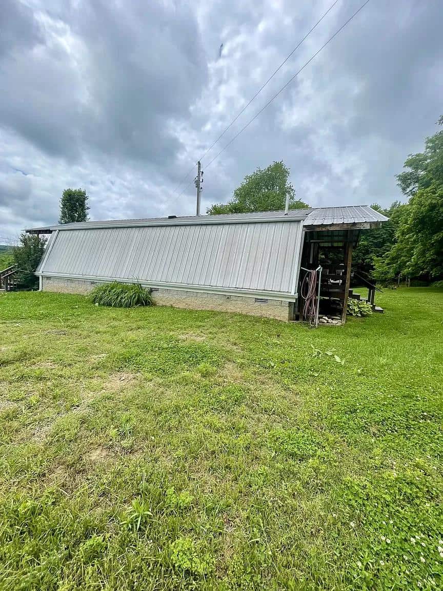 Metal-roofed tiny house with siding in a rural setting.