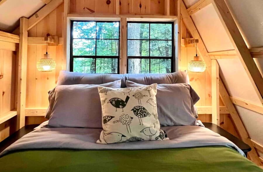 A-frame Fox Earth Cabin bedroom with large window and rustic decor.