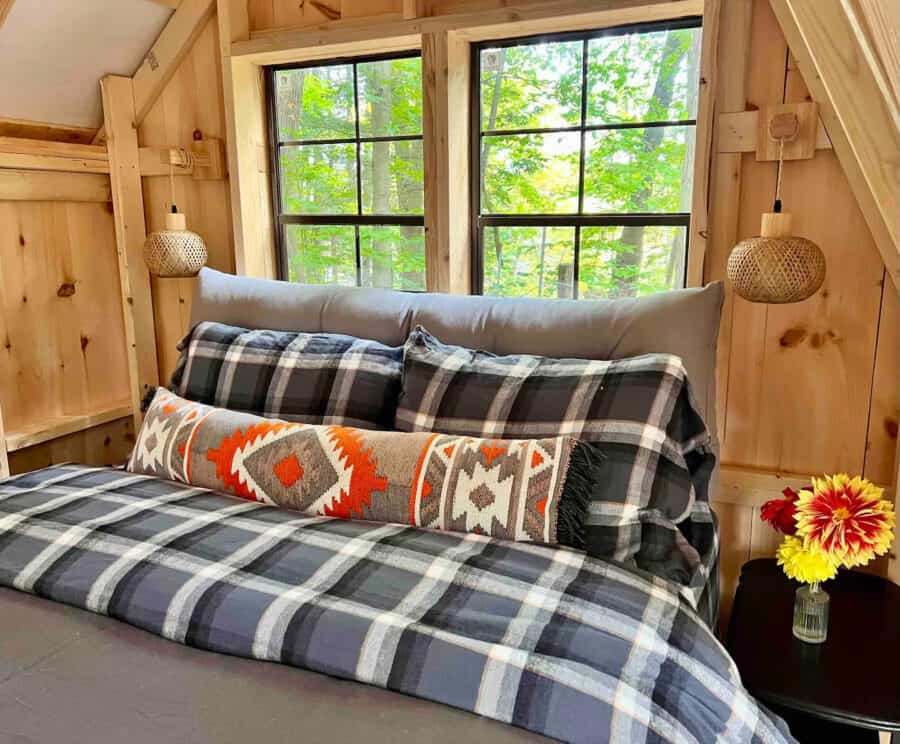 A-frame Fox Earth Cabin interior featuring cozy bedding and large windows overlooking a lush green f.
