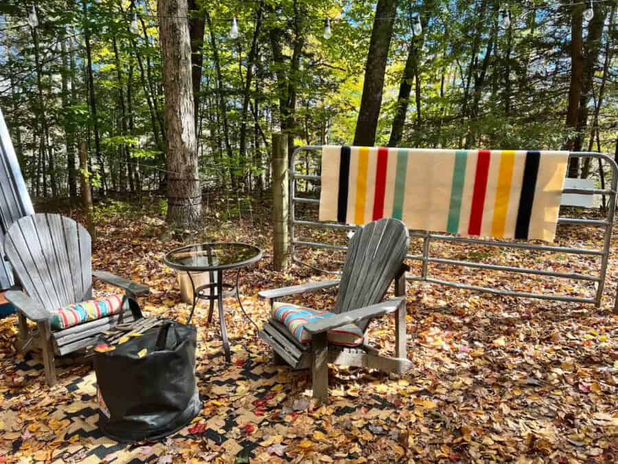 Outdoor seating with chairs, table, and blanket on Massachusetts farm.