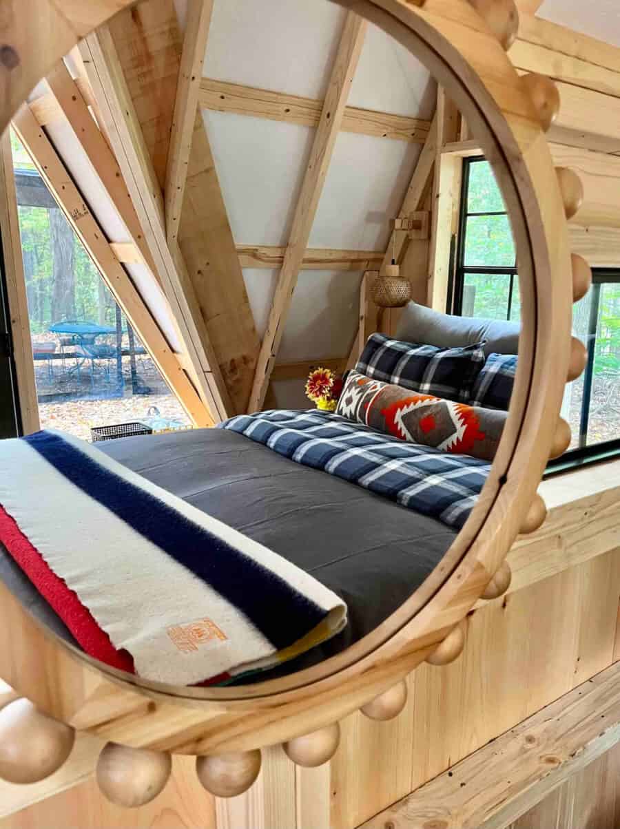A-frame Earth Cabin bedroom with rustic wooden decor and large window views.