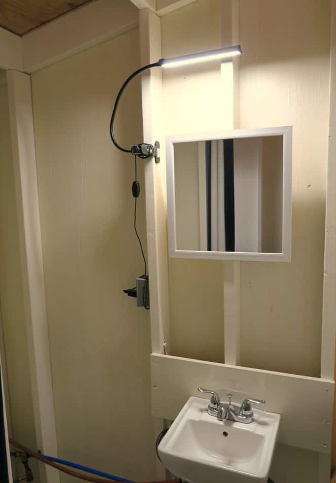 A-Frame tiny house bathroom with modern lighting and compact sink.