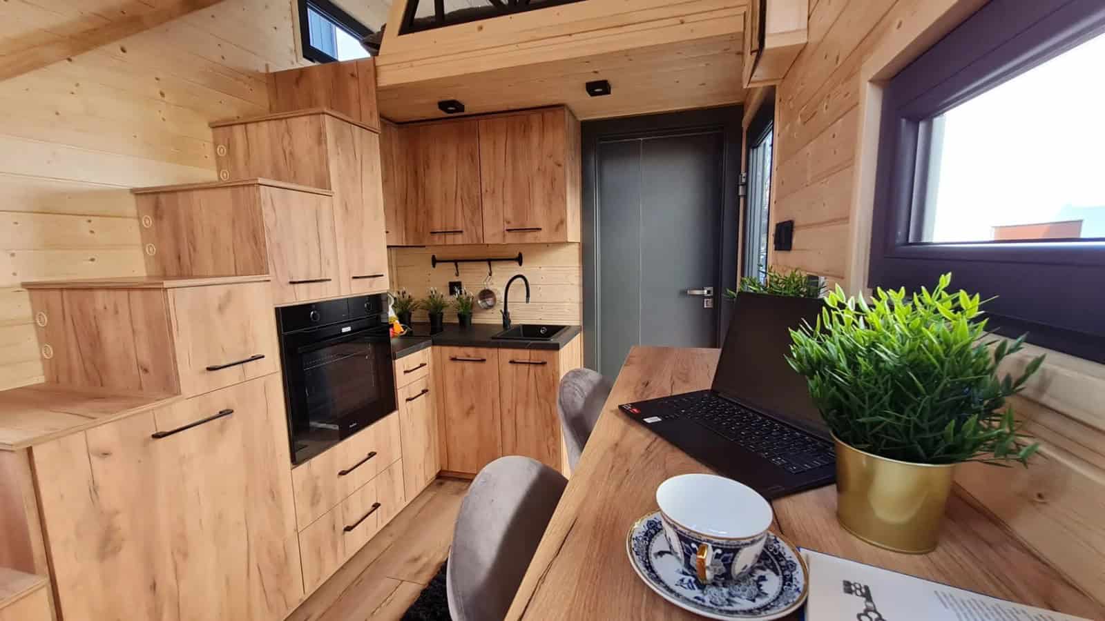 Wood dining counter set up as a workspace with a laptop in the Adams tiny house