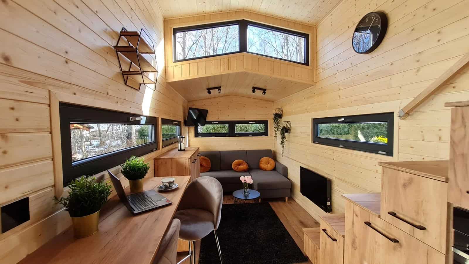 Living room of the Adams with a wood desk-dining counter, gray sofa, and TV beneath the clerestory windows