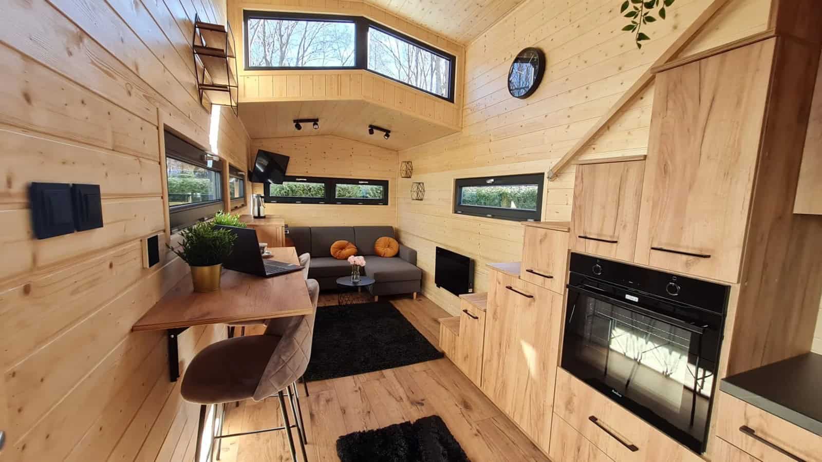 Adams tiny house interior showing the living area, a built-in oven, and storage stairs
