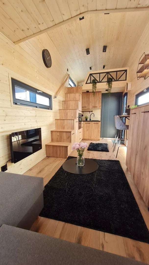 Storage staircase and steel-truss mezzanine above the kitchen in the Adams tiny house